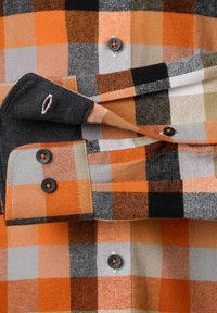 Geruite flanellen shirt met oranje, zwart, grijs en witte blokken, voorzien van contrasterende knopen en een gestructureerde stof. Mouwen met manchetten zichtbaar.