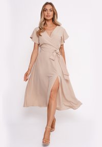 Beige Wickelkleid mit kurzen, schwingenden Ärmeln, tailliertem Bund und seitlichem Schlitz. Glattes Material mit fließendem Design.