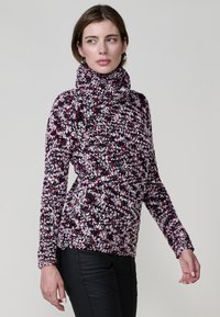 Pull en col roulé tricoté dans des teintes multicolores de rose, noir et blanc. Tissu texturé avec une coupe ample et des poignets côtelés.