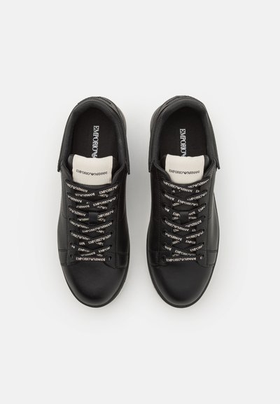 Black leather sneakers with a smooth texture, white logo on the tongue, and distinctive logo-patterned laces. Round toe and low profile design.