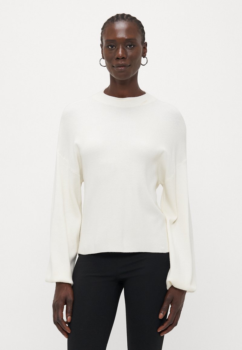 Pull léger de couleur crème avec un col montant, des manches longues amples et une coupe décontractée. Texture lisse avec un motif tricoté subtil.
