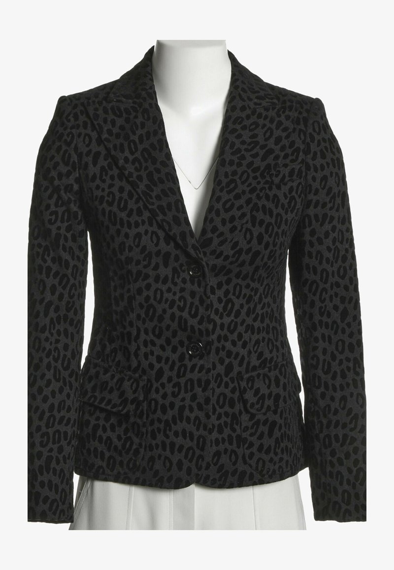 Blazer noir cintré avec motif léopard foncé, deux boutons, col à revers crantés et poches à rabat sur un torse de mannequin blanc.