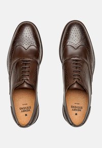 Brogue in pelle marrone con dettagli perforati, design a punta d'ala, lacci e una soletta texturizzata. Costruzione della scarpa semplice e classica.