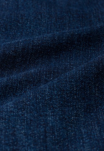 Tessuto in denim blu scuro caratterizzato da una texture liscia con sottili variazioni e un motivo intrecciato, che evidenzia la robustezza e la durata del materiale.