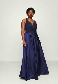 Vestido de noche azul marino con un corsé ajustado adornado con cuentas y una falda fluida. Presenta tirantes finos y un tejido texturizado y brillante.