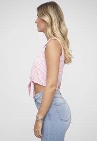 Pink gingham crop top med bindefront, kombineret med højttaljede blå cowboybukser. Toppen har tynde stropper og en afslappet pasform.