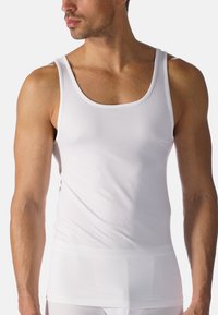 White, sleeveless tank top made of soft cotton fabric with a round neckline and fitted design, featuring minimal seams and smooth texture.