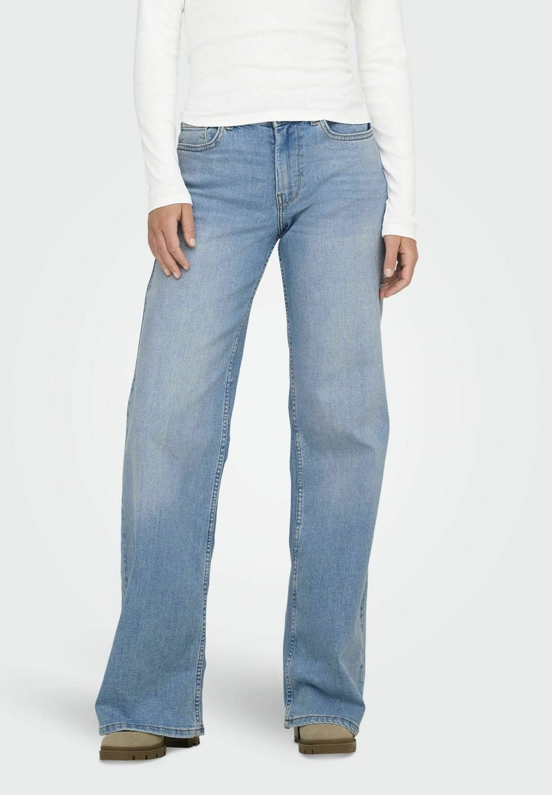 Blugi din denim albastru deschis, cu croială evazată și un design clasic cu cinci buzunare, având fermoar, bucle pentru curea și o textură ușor uzată.