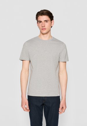 Camiseta de algodón gris de manga corta y cuello redondo, combinada con jeans de mezclilla oscuros. Diseño simple, sin patrones ni acentos visibles.
