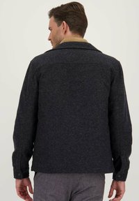 Donkergrijze wollen jas in een mix met een kraag, knoopmanchetten en stiksel details op de rug. Gelaagde afwerking met een gestructureerd ontwerp.
