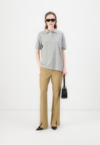 Grå polo skjorte med korte ærmer, paret med beige højtaljede bukser med sideslids. Sort håndtaske og spidse hæle inkluderet.