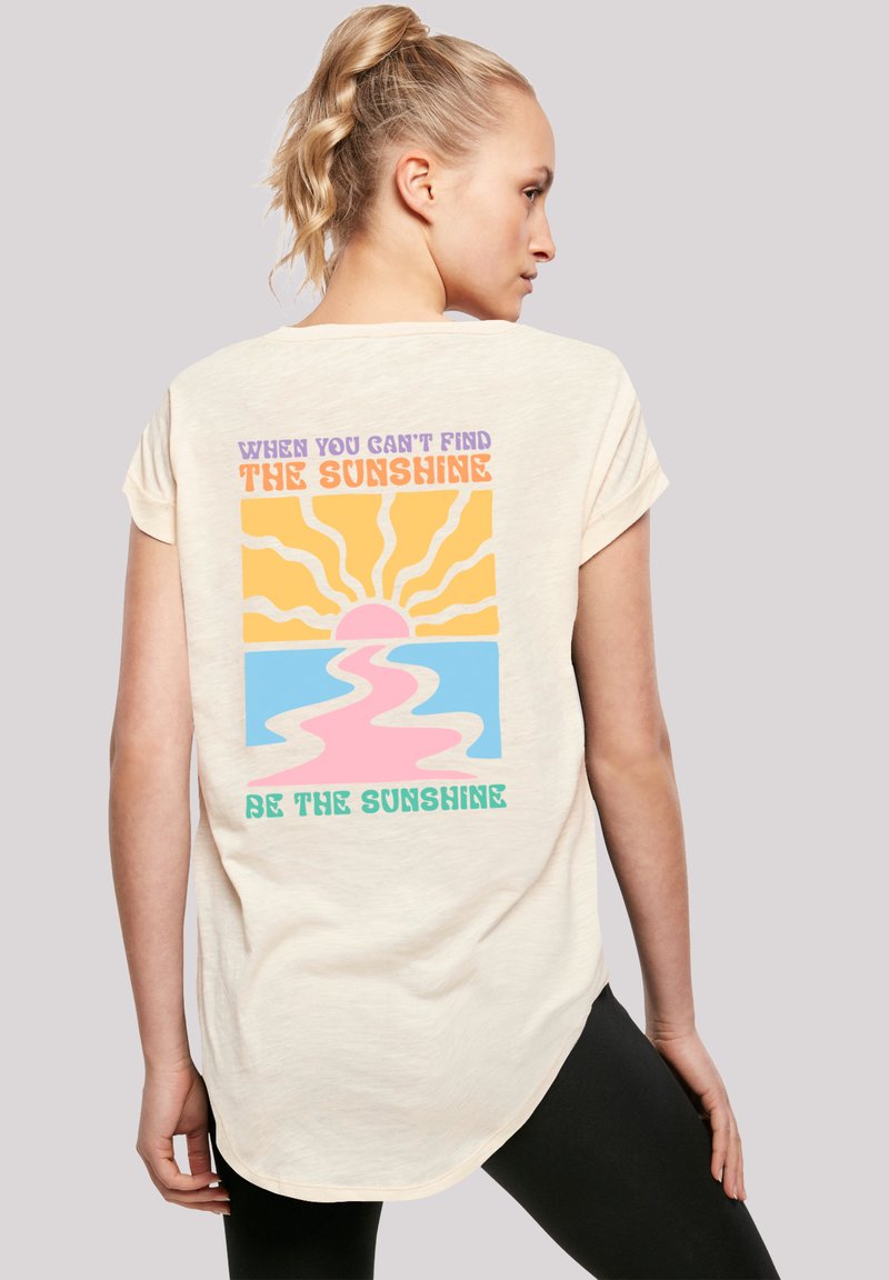 Cream-colored short-sleeve t-shirt with a colorful retro design on the back featuring a sun, waves, and text in various colors.