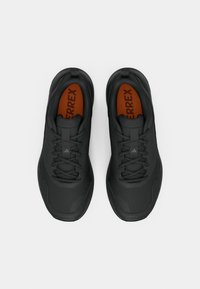 Μαύρα αθλητικά παπούτσια με υφασμένο σχέδιο, που διαθέτουν σκουρόγκρι σόλα, μαύρα κορδόνια και πορτοκαλί εσωτερική επένδυση με την επωνυμία «TERREX».