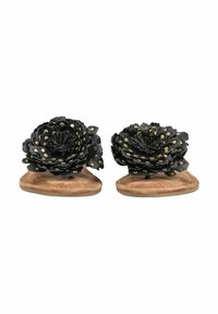 Sandales plates marron avec de grandes fleurs en cuir noir décorées de clous dorés sur les brides supérieures.