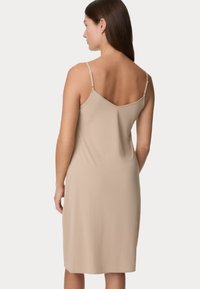 Abito slip leggero beige con spalline regolabili, design a V sulla schiena e una texture liscia e sottile. Taglio al ginocchio.