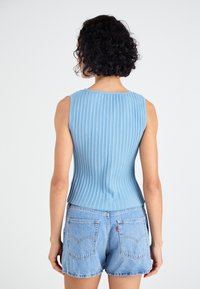 Lichtblauw geribbeld tanktop met een ronde hals, aansluitende vorm en mouwloos ontwerp, gecombineerd met denim korte broek. Gladde textuur.