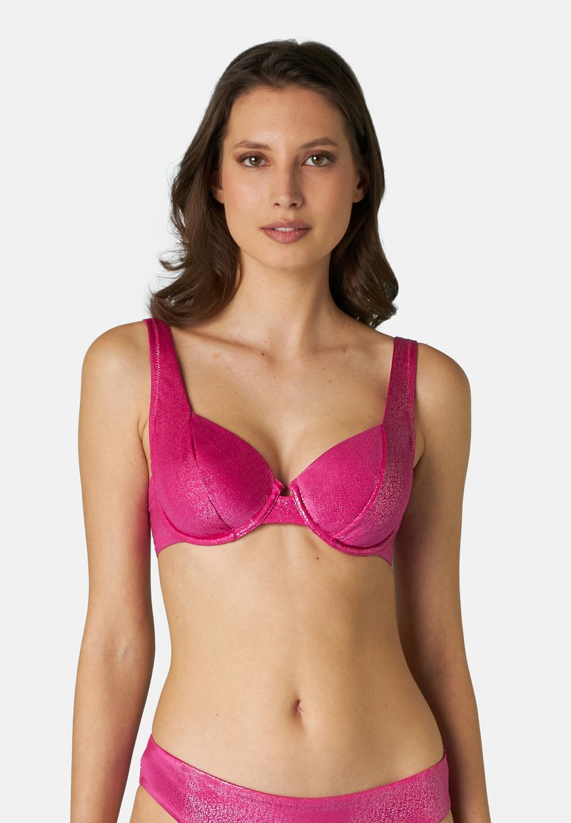 Reggiseno imbottito fucsia con una texture liscia e lucida, spalline larghe e dettaglio a fiocco centrale. Presenta supporto con ferretto e coppe strutturate.