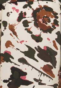 Multicolored fabric features a splatter pattern in dark green, brown, pink, and cream, with a textured finish and varied brushstroke shapes.