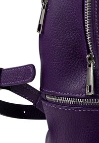 Paarse leren rugzak met een gestructureerd oppervlak, zilveren beslag en ritsen. Voorzien van een afneembare riem en gedetailleerde stiksels.