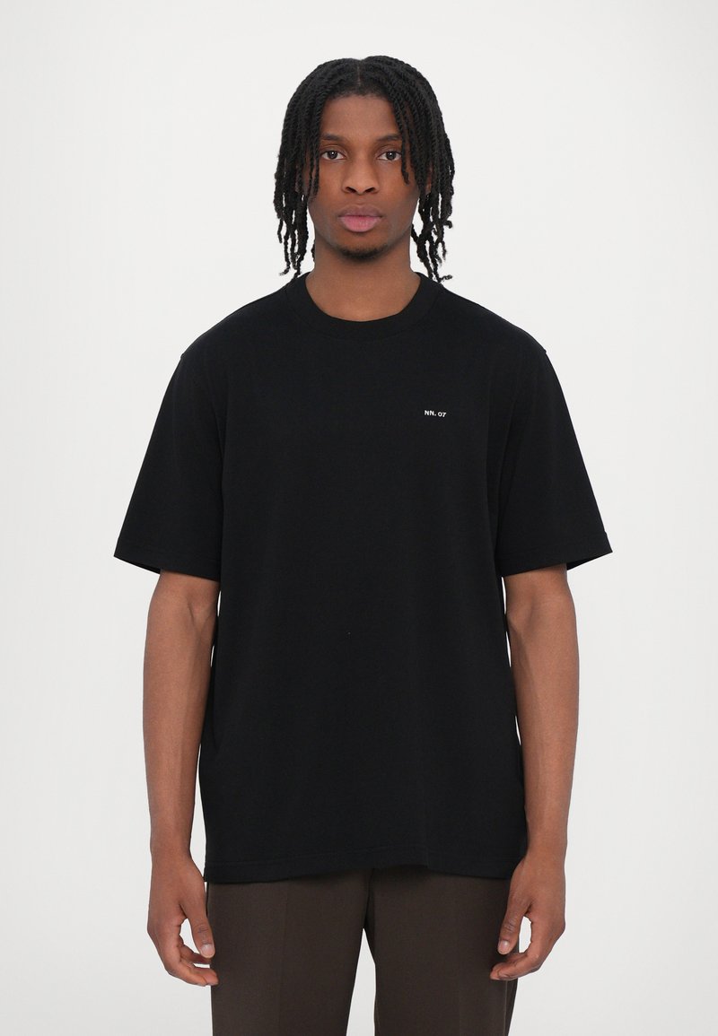 Tricou din bumbac negru, cu mâneci scurte, decolteu rotund și logo-ul subtil "NN. 07" pe piept. Textură fină și croială lejeră.