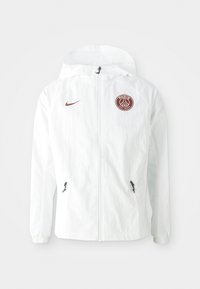 Valkoinen tuulipuku, jossa on huppu. Vasemmassa rinnassa on viininpunainen PSG-logo, sivutaskut vetoketjulla ja joustavat hihansuut.