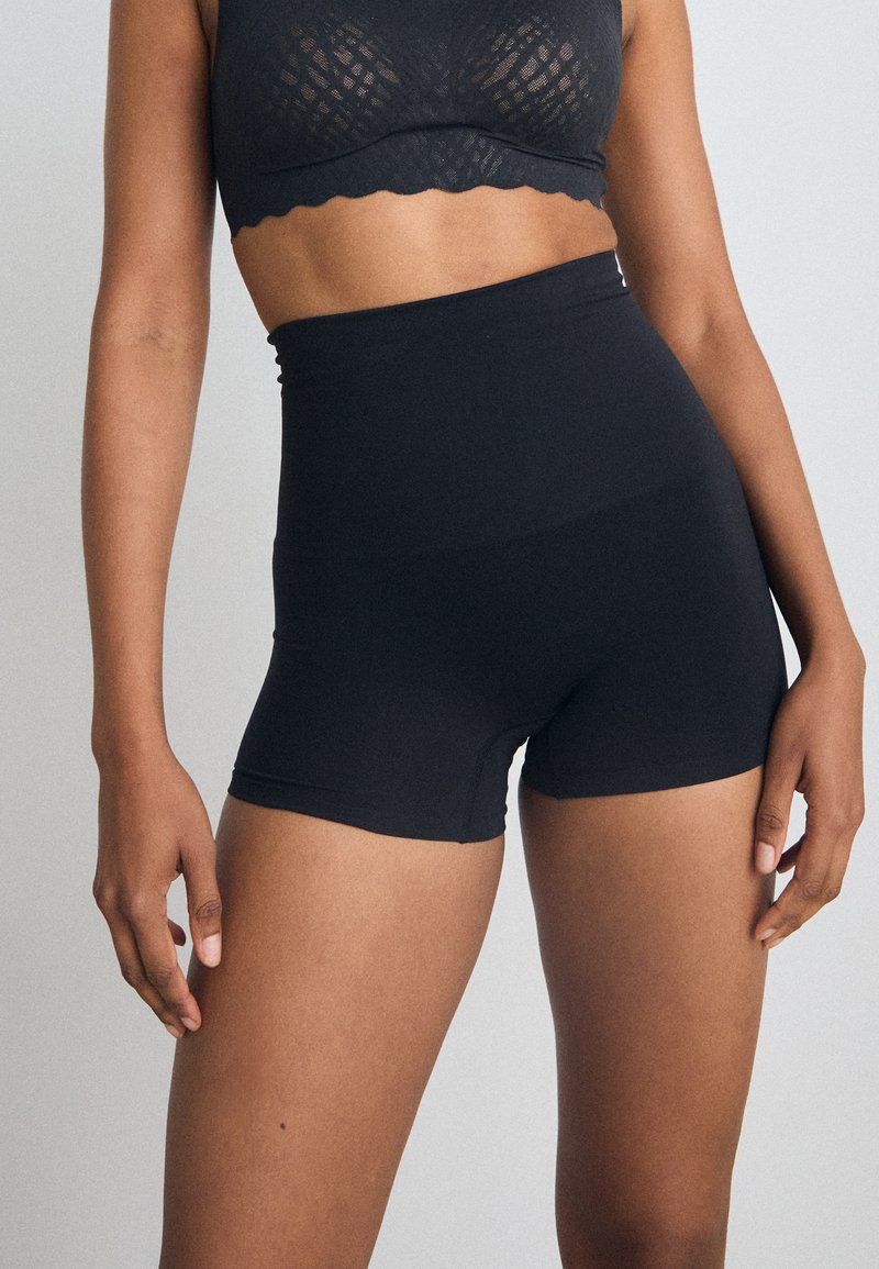 Svarte høye shorts laget av myk, elastisk stoff med en glatt tekstur. Har en tettsittende design og et rent, enkelt silhuett.