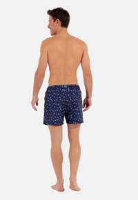 Navy Badeshorts mit einem verspielten Muster aus mehrfarbigen Motiven. Elastischer Bund mit Kordelzug. Minimalistisches Design, Medium-Länge bis zur Mitte des Oberschenkels.