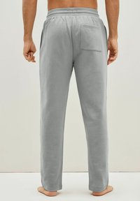 Pantalones de chándal grises de algodón con un ajuste relajado, cintura elástica y un bolsillo trasero. Textura suave y diseño de pierna recta.