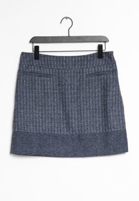Gonna in tweed blu con un motivo a spina di pesce testurizzato, taglio dritto e due tasche frontali. È appesa a un appendiabiti nero su uno sfondo bianco.