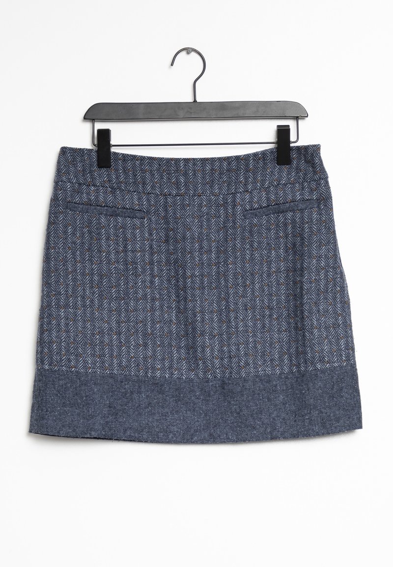 Gonna in tweed blu con un motivo a spina di pesce testurizzato, taglio dritto e due tasche frontali. È appesa a un appendiabiti nero su uno sfondo bianco.
