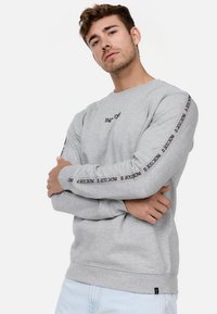 Light gray sweatshirt with long sleeves, featuring black text along the arms and a small logo on the chest. Soft cotton blend material.
