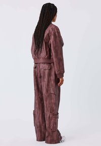 Bruine, neplederen set die bestaat uit een cropped jack en cargobroek. De stof heeft een gemêleerde, gestructureerde afwerking en bevat utiliteitspockets.