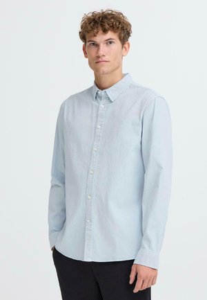 Light blue button-up shirt made of soft fabric, featuring a classic collar, long sleeves, and a small logo on the chest.