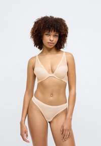 Light beige lingerie set featuring a bra with a smooth, molded design and delicate mesh panels, paired with matching sheer thong.