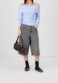 Maglione a righe blu chiaro senza spalline, pantaloni corti in denim grigi a gamba larga, calze nere, ballerine con stampa leopardata e una borsa a tracolla marrone scuro.