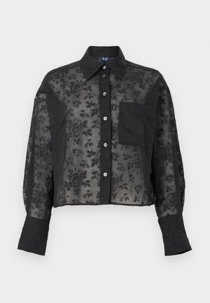 Blouse noire transparente à motifs floraux, manches longues, boutonnée, avec col, poche poitrine et larges poignets.