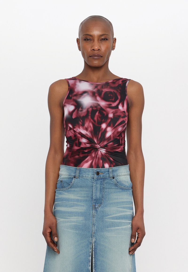 Top sin mangas de patrón floral en negro y rojo con un diseño en espiral, combinado con una falda de mezclilla azul clara con una abertura frontal y bolsillos.