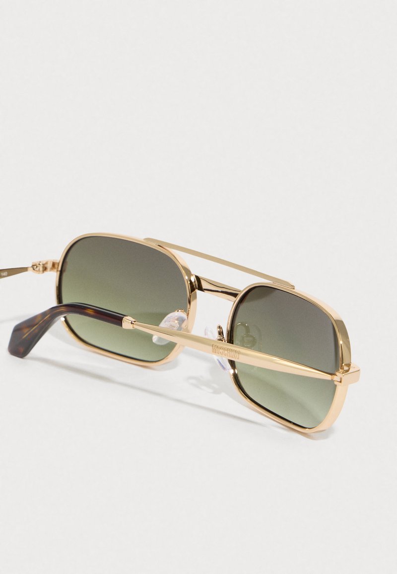 Occhiali da sole in metallo dorato con lenti rettangolari, sfumatura verde gradiente e templi accentuati in marrone, dotati di un supporto per il naso per il comfort.