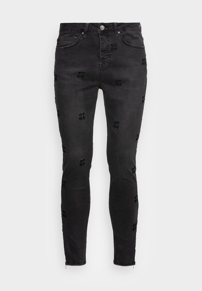 Black denim skinny jeans featuring embossed text patterns, five pockets, and a zippered ankle detail. Classic cut and sturdy fabric.