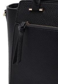 Black textured leather handbag with front zip pocket and long leather tassel pull, featuring gold-tone hardware accents.