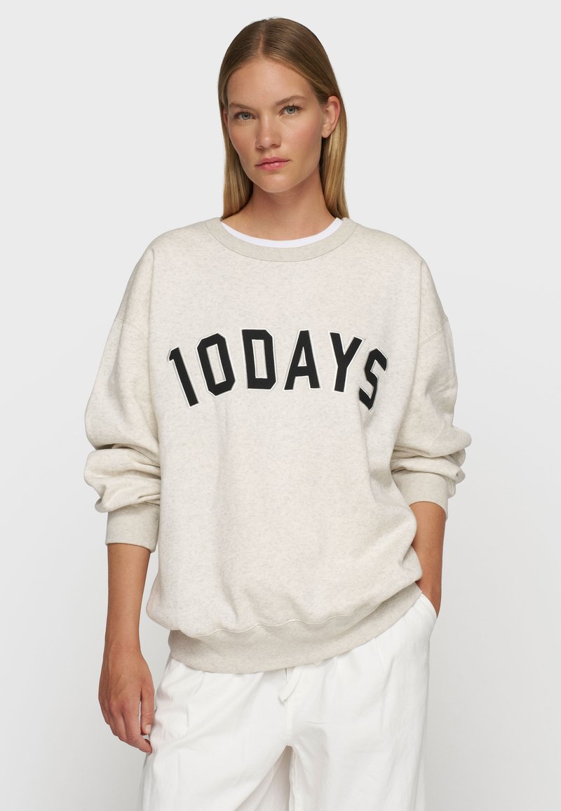 Helle beige Oversized-Sweatshirt mit schwarzer "10DAYS" Schriftzug, gerippten Bündchen und Saum. Der Stoff wirkt weich und hat eine lockere Passform.