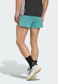 Turquoise athletic shorts with a lightweight, breathable material. Black crew socks and white sneakers with black accents and textured soles.