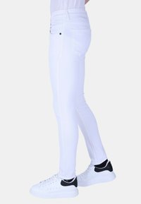 Witte skinny jeans van denim, met een zachte textuur, traditionele vijf-pocketdesign en contrasterende zwarte hardwareaccenten.