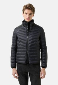 Kurtka puchowa w ciemnym granacie z poziomym pikowaniem, wysokim kołnierzem, zamkiem błyskawicznym i bocznymi kieszeniami. Lekki materiał o gładkiej fakturze.