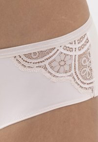 Intimo da donna color beige chiaro con una finitura liscia, caratterizzato da dettagli in pizzo floreale sui lati e un delicato bordo lungo il pizzo.