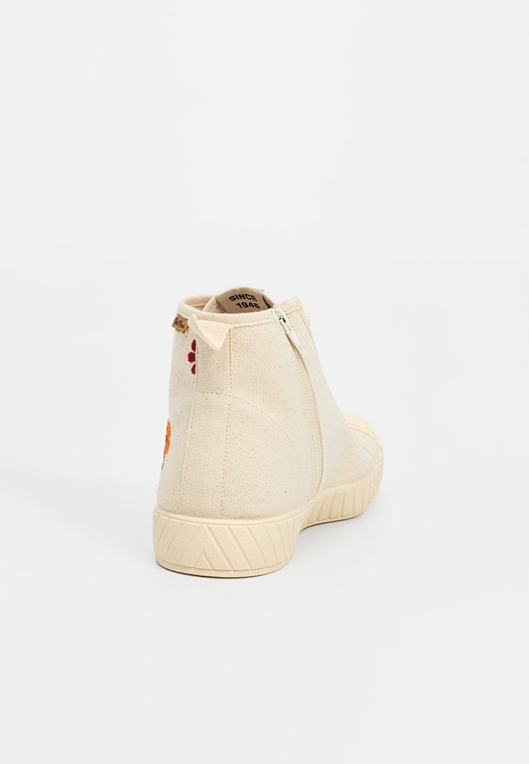 Baskets montantes en toile blanc cassé avec fermeture éclair sur le côté, semelle texturée et détails floraux brodés orange et rouge sur le talon.