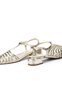 Las sandalias de tacón alto en un dorado metálico cuentan con un diseño entrelazado con lados abiertos y una correa ajustable en el tobillo. Tacón grueso para mayor estabilidad.