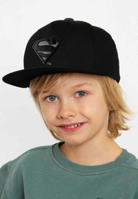 Black cap made of fabric featuring a raised black Superman logo on the front. Flat brim and adjustable snapback closure.