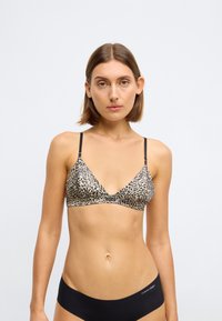 Leopardprint bralette met een driehoekige vorm, lichte stof, slanke zwarte bandjes en een subtiel logo op de voorkant. Zwarte naadloze onderbroek.