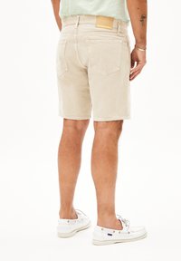 Beige denim shorts met een rechte snit, achterzakken en een branded tan leren label. Draagbare witte schoenen, die een casual stijl benadrukken.